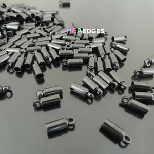 May include: A large quantity of black metal end caps with a loop on one end and a ball on the other. These end caps are used for jewelry making and other crafts.