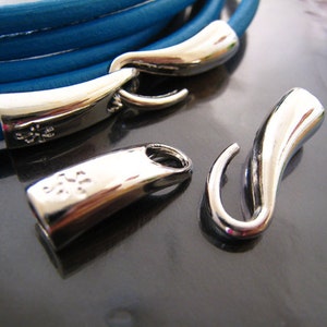 May include: Close-up of a turquoise leather bracelet with silver-toned clasps and a hook closure. The bracelet is made of multiple strands of leather and has a simple, elegant design.