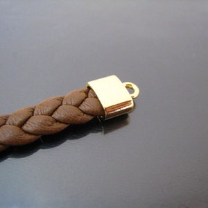 May include: A brown leather braided bracelet with a gold metal clasp.