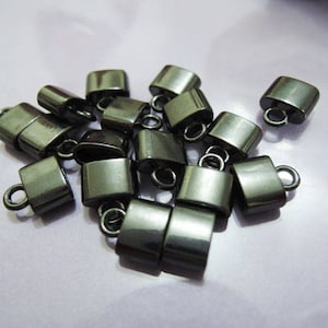 May include: A group of 14 black metal end caps with a small loop on each. The end caps are in a pile on a light purple surface.