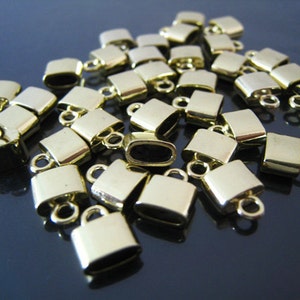 May include: A group of gold-colored metal end caps for jewelry making. The end caps are square shaped with a small loop on one side.