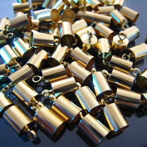 May include: A large group of gold-colored metal end caps for jewelry making. The end caps have a small loop on one end for attaching to a chain or cord.
