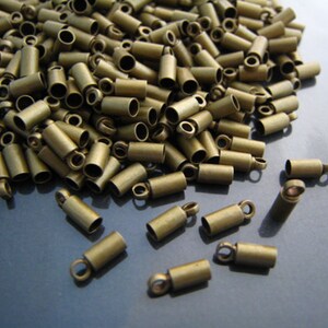 May include: A large pile of gold-toned metal end caps for cords or jewelry making. The end caps have a small loop at the top.