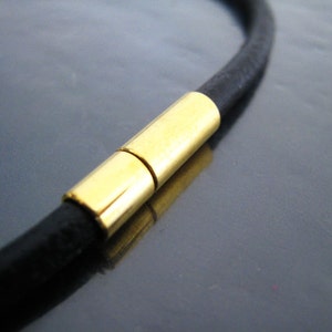 May include: A black leather cord necklace with a gold magnetic clasp.