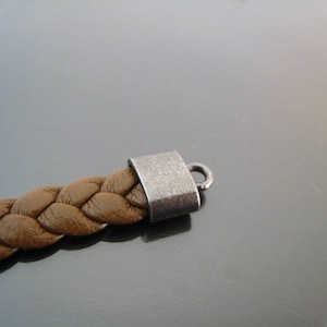 May include: A brown leather braided bracelet with a silver metal clasp.