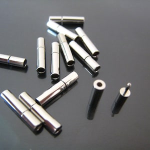 May include: A group of silver-toned metal connector tubes, some are open and some are closed. There are also two smaller silver-toned metal tubes with a pointed end.