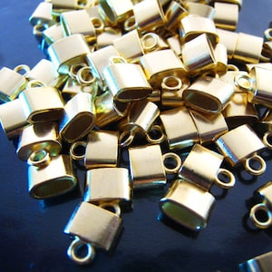 May include: A pile of gold-colored metal end caps for cords or straps. The end caps have a small loop on one end.