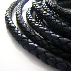 May include: Close-up of black braided leather cord. The cord is woven in a tight, intricate pattern. The leather is smooth and supple.