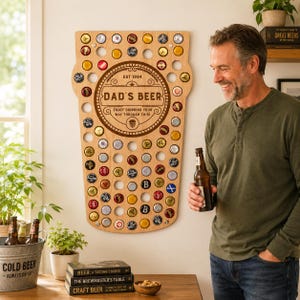 May include: A wooden beer cap holder shaped like a beer glass, with the text "DAD'S BEER" and "EST 1984". The holder is filled with various beer bottle caps. A man is holding a beer bottle next to the holder.