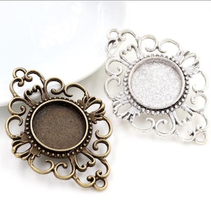 May include: Two ornate metal frames with a round, clear glass insert. The frames are in a diamond shape with intricate scrollwork. One frame is silver and the other is bronze.