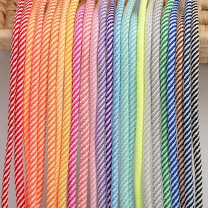 May include: A collection of 20 colorful striped cords with white stripes. The cords are arranged in a rainbow pattern.