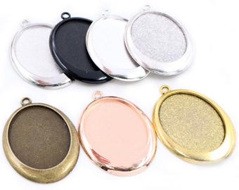May include: Six oval-shaped metal pendant trays with a silver, black, gold, rose gold, and two bronze finishes. The trays have a smooth, shiny surface and are ready to be filled with resin or other crafting materials.