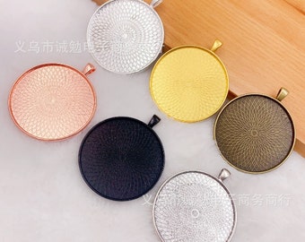 Op de afbeelding: Zes ronde metalen hanger-schalen met een decoratief patroon. De schalen zijn in zilver, goud, rosé goud, zwart en twee tinten zilver.