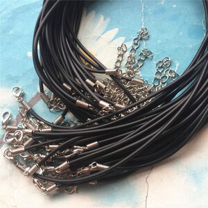 May include: A pile of black elastic cord necklaces with silver lobster clasps. The cords are arranged in a loose bundle, with some of the cords overlapping.