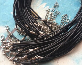 Puede incluir: Un montón de collares de cordón elástico negro con cierres de langosta plateados. Los cordones están dispuestos en un paquete suelto, con algunos cordones superpuestos.