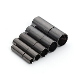 May include: A set of seven black magnetic clasps for jewellery making. The clasps are different sizes and are arranged in a row from largest to smallest.