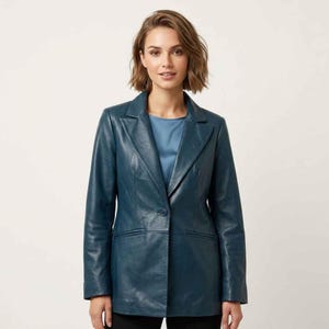Puede incluir: Blazer de cuero color turquesa con solapa de muesca clásica y cierre de un solo botón. El blazer tiene dos bolsillos delanteros y un corte entallado. La modelo lleva un top azul. Una prenda de vestir exterior elegante.