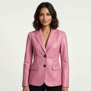 Puede incluir: Una blazer de cuero rosa con solapa de muesca clásica, cierre de dos botones y dos bolsillos delanteros. La blazer es de color liso y tiene un corte entallado. La modelo lleva un collar de oro.