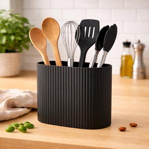 Könnte beinhalten: Ein Set aus drei Keramikbechern mit gesprenkelter, matter Oberfläche. Die Becher sind in Creme-, Hellgrau- und Dunkelgrautönen gehalten. Jeder Becher hat ein schlichtes, minimalistisches Design, ideal für Kaffee oder Tee.