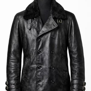 May include: A black leather coat with a faux fur collar. The double-breasted coat features multiple buttons, two front pockets, and adjustable straps on the sleeves. The coat is displayed on a mannequin.
