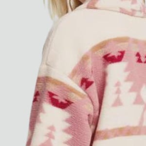 May include: Cream-colored jacket with a geometric pattern in shades of pink and red. The jacket features a high collar and a soft, textured fabric. The design includes triangular and abstract shapes.