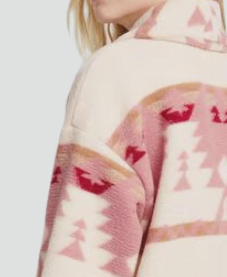 May include: Cream-colored jacket with a geometric pattern in shades of pink and red. The jacket features a high collar and a soft, textured fabric. The design includes triangular and abstract shapes.