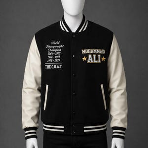 Puede incluir: Chaqueta universitaria negra y crema con el nombre "MUHAMMAD ALI" y el texto "World Heavyweight Champion" bordados en la parte delantera. La chaqueta tiene mangas color crema, cuerpo negro y puños y dobladillo a rayas blancas y negras.