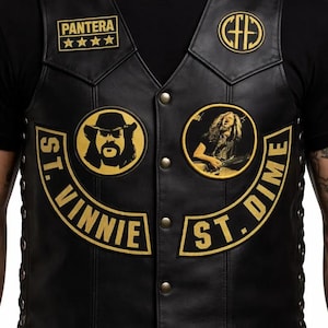 May include: Black leather vest with various patches. Patches feature the band name "Pantera" with stars, a circular logo, and two patches with portraits and the text "St. Vinnie" and "St. Dime" in gold lettering.