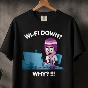 Può includere: T-shirt nero con una grafica di una persona che guarda un computer con la scritta "WI-FI DOWN? WHY? !!!". La persona ha un casco viola e bianco ed è seduta a una scrivania con un laptop e un telefono.