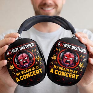 May include: Black headphones with the text "DO NOT DISTURB" and "MY BRAIN IS AT A CONCERT". The design features a cartoon brain wearing headphones, surrounded by musical notes and lightning bolts.