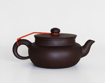 Tetera china Yixing antigua: tetera de arcilla marrón oscuro con tapa de cordón naranja.