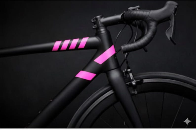 May include: A black road bicycle with pink accents. The frame is matte black with bright pink stripes and angled accents. The handlebars and tires are black, set against a dark background.