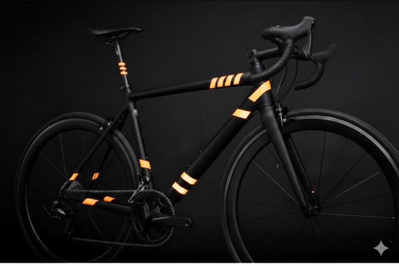 May include: A sleek black road bike with orange reflective stripes on the frame and seat post. The bike has black wheels and handlebars, set against a dark background. The design emphasizes a modern, minimalist aesthetic.