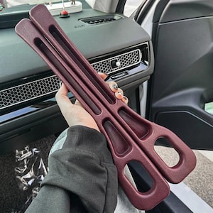 Puede incluir: Dos rellenos de espacio para asientos de coche de pl&aacute;stico texturizado en color granate oscuro, con un dise&ntilde;o curvo y liso. Cada pieza presenta una ranura larga y estrecha y una abertura redondeada en la base.
