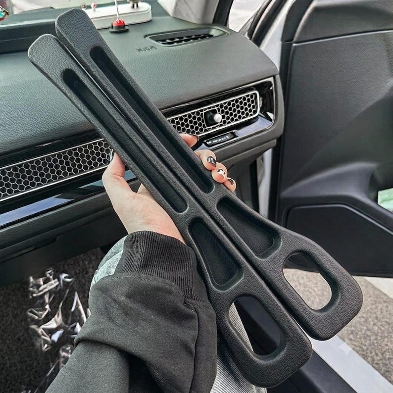 Puede incluir: Un par de ganchos de pl&aacute;stico negro mate para el reposacabezas del coche, con un dise&ntilde;o largo y delgado con m&uacute;ltiples ranuras recortadas para organizar objetos. Los ganchos tienen una superficie texturizada y una forma curva para el asiento.