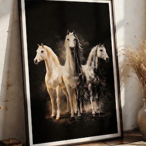 May include: A framed art print featuring three horses against a dark background. The horses are depicted in shades of white, gray, and cream, with flowing manes and tails. The artwork is displayed in a black frame, leaning against a wall.