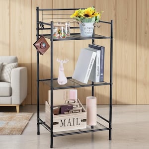 Könnte beinhalten: Schwarzes Metallregal mit drei Drahtböden. Auf der obersten Ablage stehen ein kleiner Eimer mit Sonnenblumen, ein Glas und ein dekorativer Haken. Die Regale zeigen Bücher, Dekorationsartikel und eine Holzkiste mit dem Wort "MAIL".