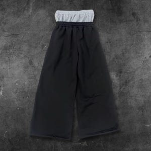 May include: Black wide-leg pants with a gray waistband. The pants have a relaxed fit and a casual style. The waistband is a contrasting color, adding a visual detail to the design. The pants are made of a soft material.