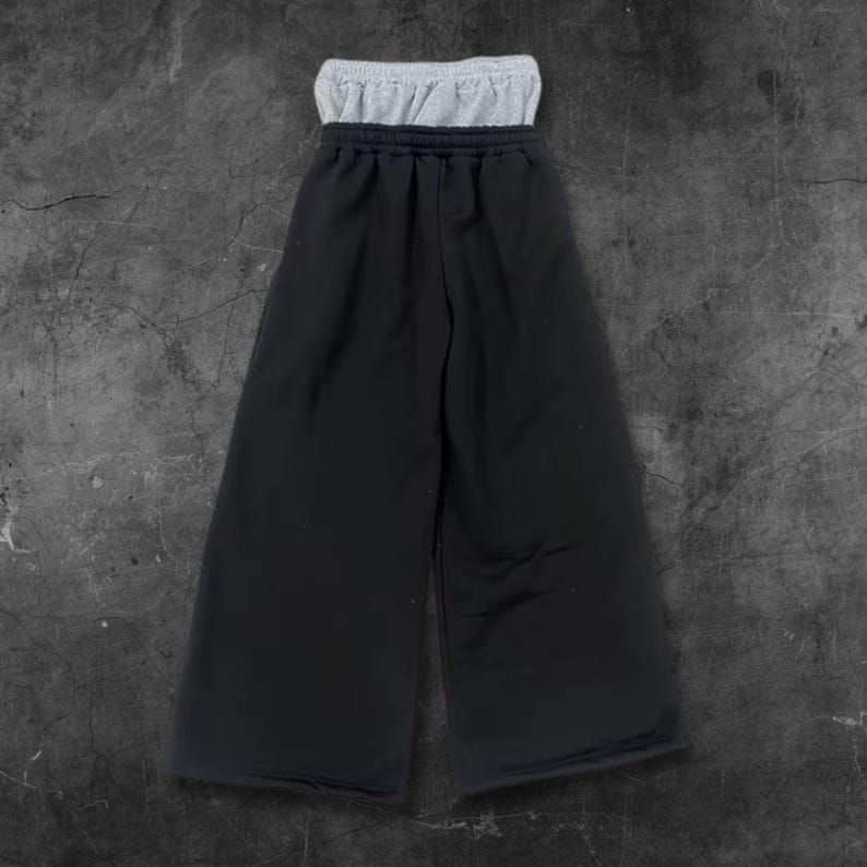 May include: Black wide-leg pants with a gray waistband. The pants have a relaxed fit and a casual style. The waistband is a contrasting color, adding a visual detail to the design. The pants are made of a soft material.