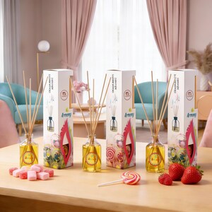 Puede incluir: Cuatro difusores de aromaterapia de vidrio con varillas de madera, cada uno con una caja con la palabra "Armony". Los difusores están sobre una mesa de madera con caramelos y fresas. Las cajas tienen el texto "Olfato Ambiente Agradable".