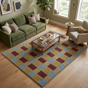 May include: A rectangular area rug featuring a repeating checkered pattern in muted shades of mustard yellow, light blue, and deep burgundy. The rug has a textured, tufted surface and is positioned on a light-toned wooden floor in a living room.