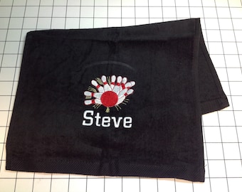 May include: Black towel with embroidered bowling pins and a red ball in the center. The name "Steve" is embroidered below the bowling pins.