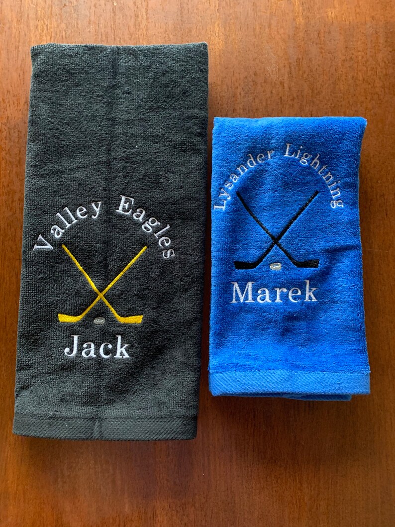May include: Two embroidered towels, one black with the text "Valley Eagles" and the name "Jack" and the other blue with the text "Lysander Lightning" and the name "Marek".