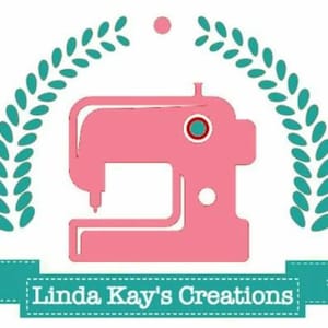 May include: A pink sewing machine with a teal wreath and the text "Linda Kay's Creations" on a teal banner.