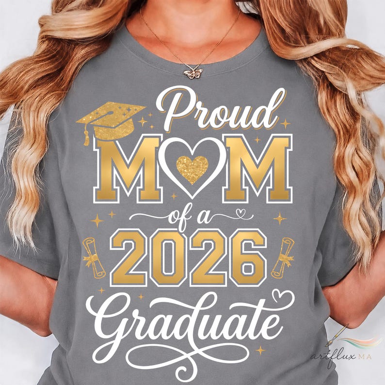 May include: A grey t-shirt with gold text reading "Proud MOM of a 2026 Graduate." The design features a graduation cap, heart, and diploma illustrations. The shirt has a crew neck.