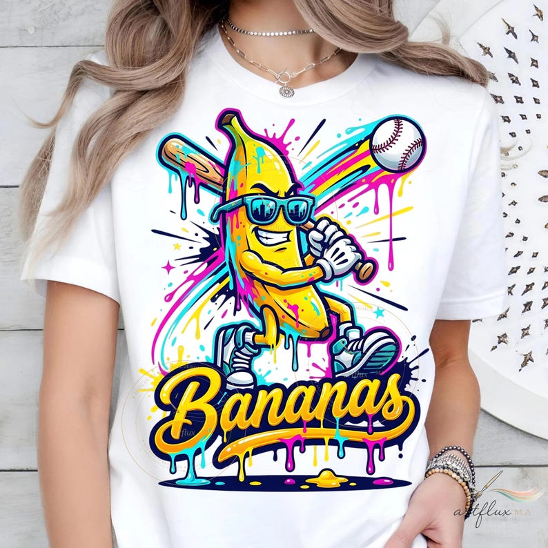 May include: White t-shirt with a cartoon banana wearing sunglasses and playing baseball. The banana is yellow with blue, pink, and green accents. The word "Bananas" is written in a yellow, dripping font.
