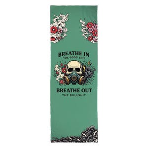 May include: A rectangular sage green mat featuring a central graphic of a skull wearing a gas mask, surrounded by red and pink flowers and smoke. The text reads BREATHE IN THE GOOD SHIT and BREATHE OUT THE BULLSHIT in black capital letters.