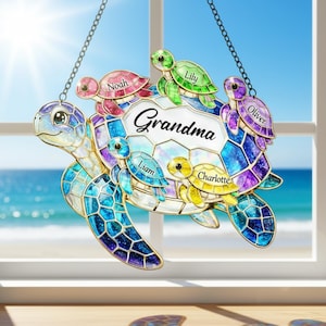 May include: A stained glass turtle suncatcher with the word "Grandma" and the names Noah, Lily, Oliver, Liam, and Charlotte. The turtle is blue, purple, and yellow with a chain for hanging. The background is a window with a beach view.