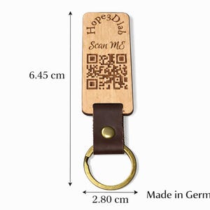 Könnte beinhalten: Holzschlüsselanhänger mit braunem Lederriemen und goldfarbenem Ring. Das Holzschild trägt den Text "Hope3Dlab" und "Scan Me" mit einem QR-Code. Der Schlüsselanhänger ist 6,45 cm lang und 2,80 cm breit.