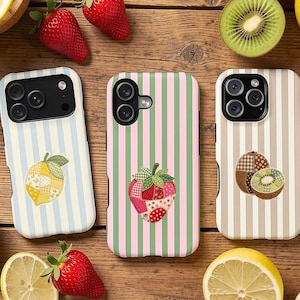 Puede incluir: Tres fundas para smartphone con rayas verticales y diseños de frutas en patchwork. La funda izquierda tiene rayas azules y un limón, la central rayas verdes y rosas con una fresa, y la derecha rayas beige con un kiwi.